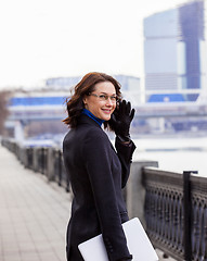 Image showing friendly brunette with a computer outdoors