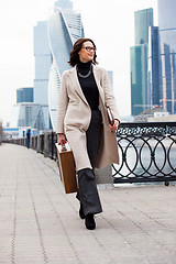 Image showing woman with a wooden case in his hand in the bright coat