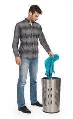 Image showing Young man putting a dirty towel in a laundry basket