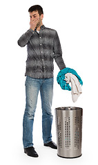 Image showing Young man putting a dirty towel in a laundry basket