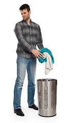 Image showing Young man putting a dirty towel in a laundry basket