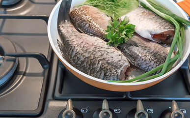 Image showing Fish and components for her preparation in a large skillet.