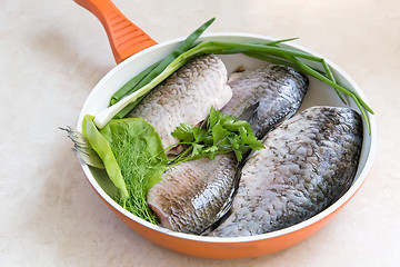 Image showing Fish and components for her preparation in a large skillet.