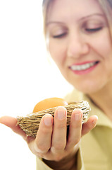 Image showing Mature woman holding a nest with an egg