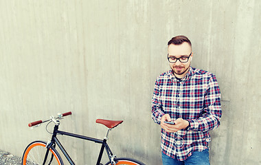 Image showing hipster man in earphones with smartphone and bike