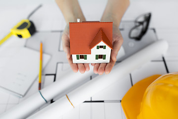 Image showing close up of hands with house model above blueprint