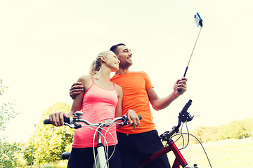 Image showing couple with bicycle and smartphone selfie stick