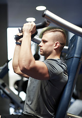 Image showing man exercising and flexing muscles on gym machine