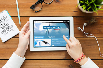 Image showing close up of woman with tablet pc on wooden table