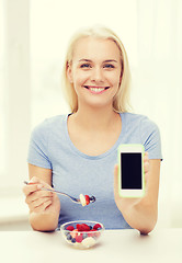 Image showing woman with smartphone eating fruits at home