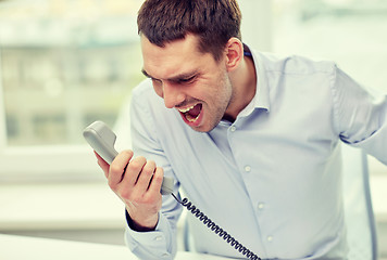 Image showing furious businessman calling on phone in office