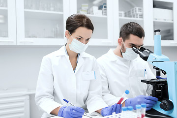 Image showing scientists with clipboard and microscope in lab