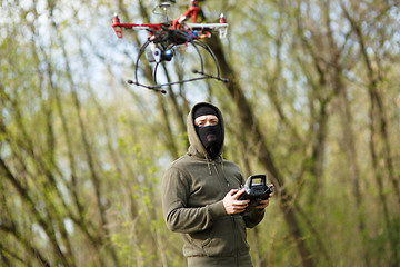 Image showing Man in mask operating a drone with remote control.