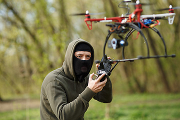 Image showing Man in mask operating a drone with remote control.