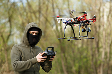 Image showing Man in mask operating a drone with remote control.