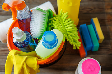 Image showing Plastic bucket with cleaning supplies on wood background