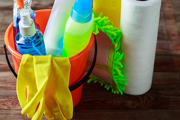 Image showing Plastic bucket with cleaning supplies on wood background