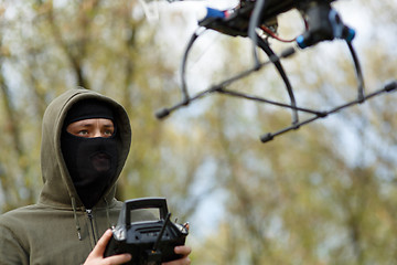 Image showing Man in mask operating a drone with remote control.