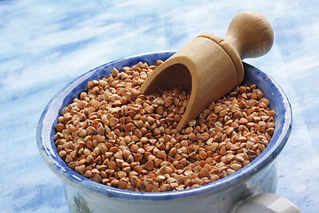 Image showing Buckwheat seeds into ceramic cup with wooden scoop