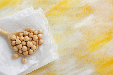 Image showing Still life with chickpea seeds on wooden spoon and paper cloth