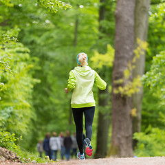Image showing Sporty young female runner in the forest. 