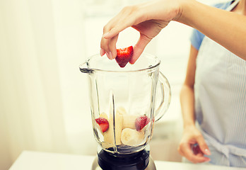 Image showing close up of woman with blender making fruit shake