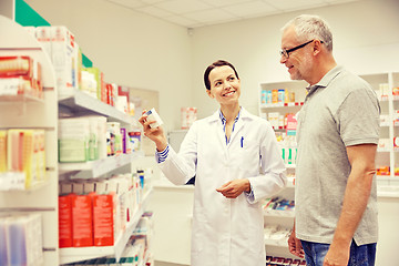 Image showing pharmacist showing drug to senior man at pharmacy