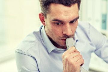 Image showing face of businessman with phone receiver in office