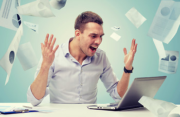 Image showing angry businessman with laptop and papers shouting