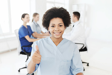 Image showing happy female doctor or nurse showing thumbs up