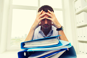 Image showing sad businessman with stack of folders at office