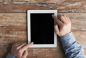 Image showing close up of male hands with tablet pc on table