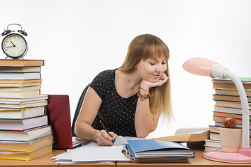 Image showing Pretty teenage girl has been at the table cluttered with books in the library