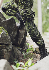 Image showing close up of soldier climbing on rocks in forest