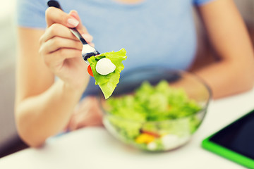 Image showing close up of young woman eating salad at home