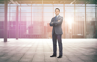 Image showing smiling businessman over empty hall and city