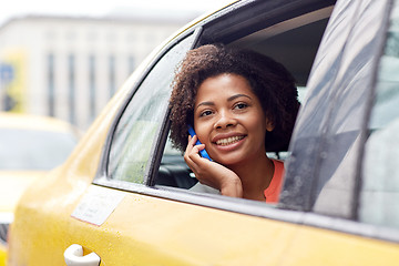 Image showing happy african woman calling on smartphone in taxi