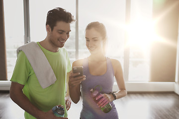 Image showing happy woman and trainer showing smartphone in gym