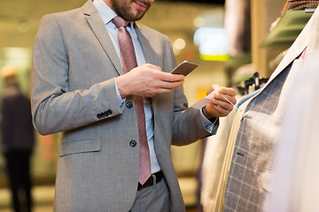 Image showing close up of man with smartphone at clothing store