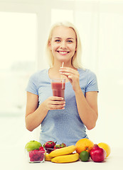 Image showing smiling woman drinking fruit shake at home