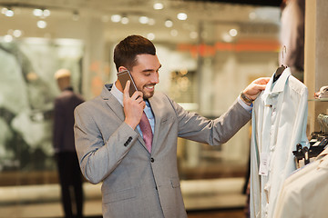 Image showing happy man calling on smartphone at clothing store