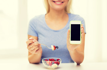 Image showing close up of woman with smartphone eating salad