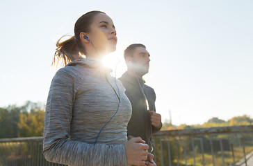 Image showing happy couple with earphones running outdoors