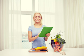 Image showing smiling young woman with tablet pc cooking at home