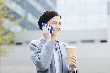 Image showing smiling woman with coffee calling on smartphone