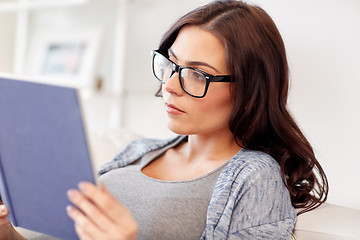 Image showing young woman in glasses reading book at home