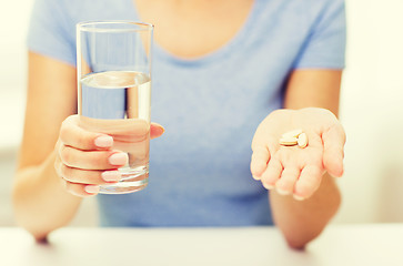 Image showing close up of woman hands with pills and water