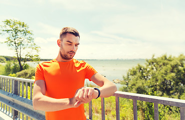 Image showing young man with smart wristwatch at seaside