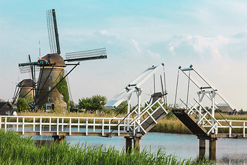 Image showing beautiful traditional dutch windmills near the water channels with drawbridge