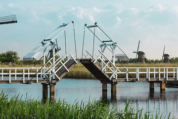 Image showing beautiful traditional dutch windmills near the water channels with drawbridge